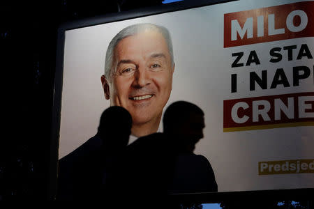 People walk past an election billboard of the presidential candidate Milo Djukanovic, in Podgorica Montenegro, April 14, 2018. REUTERS/Marko Djurica