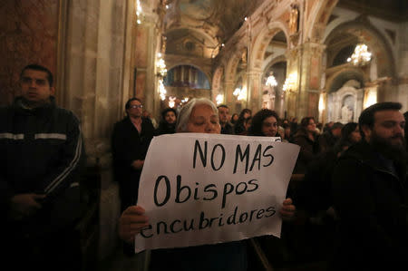 A woman holds a banner that reads, "No more bishops covering-up" as Archbishop of Santiago Ricardo Ezzati (not pictured) attends his religious service after he was summoned to testify in an investigation into the alleged cover-up of child sexual abuse by members of the Catholic Church, at the Santiago cathedral, in Santiago, Chile, July 25, 2018. REUTERS/Ivan Alvarado