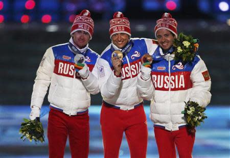 Russia's gold medallist Alexander Legkov poses with compatriots silver medallist Maxim Vylegzhanin (L) and bronze medallist Ilia Chernousov (R) after being presented with medals for the men's cross-country 50km mass start free event during the closing ceremony of the 2014 Sochi Winter Olympics, February 23, 2014. REUTERS/Phil Noble