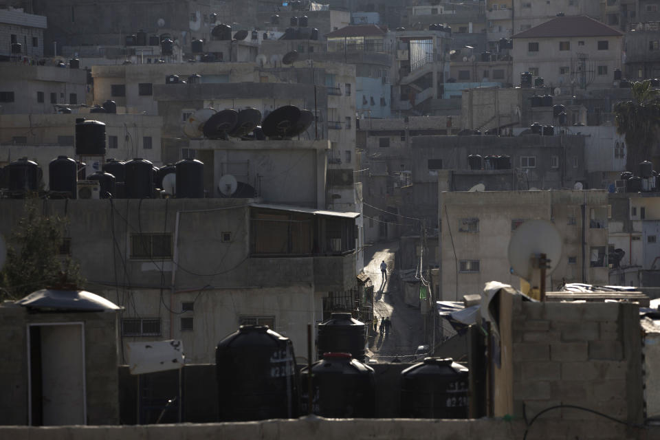 In this April 3, 2014 photo, water tanks are seen on rooftops as a Palestinian walk in an alley in Shuafat in east Jerusalem. Tens of thousands of Palestinians in east Jerusalem have been without water for more than a month, victims of a decrepit and overwhelmed infrastructure and caught in a legal no-man’s land. Their district is technically part of Jerusalem municipality, but on the other side of the massive Israeli-built West Bank separation barrier, so Israeli services there are sparse yet Palestinian officials are barred for operating. With the scorching summer approaching, residents are growing increasingly desperate. (AP Photo/Sebastian Scheiner)