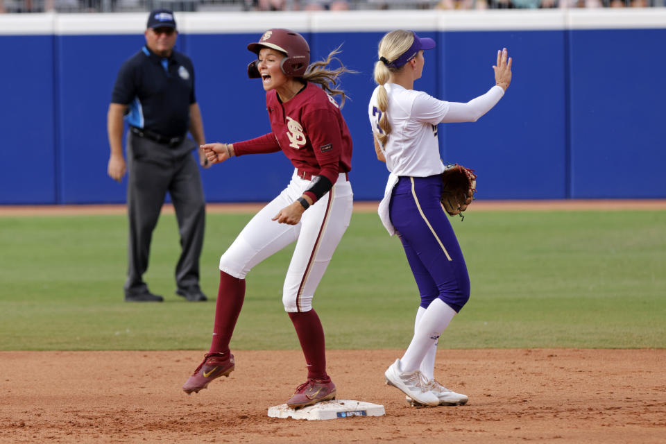 Florida State's Devyn Flaherty, front left, celebrates near Washington's Rylee Holtorf, right, after hitting a double during the second inning of an NCAA softball Women's College World Series game Saturday, June 3, 2023, in Oklahoma City. (AP Photo/Nate Billings)
