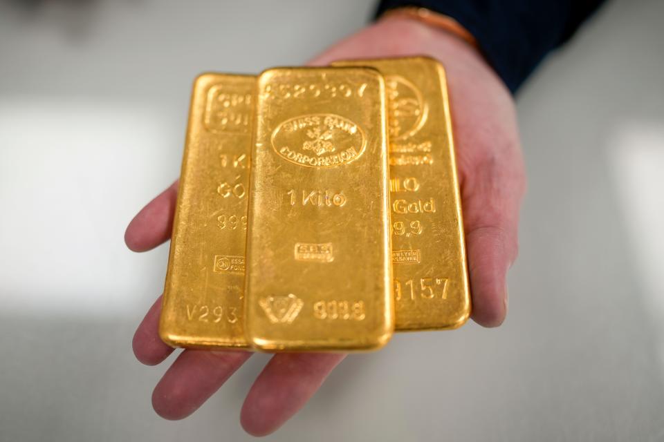 A jewellery quarter gold dealer poses with three 1kg gold bullion bars on December 13, 2023 in Birmingham, England.