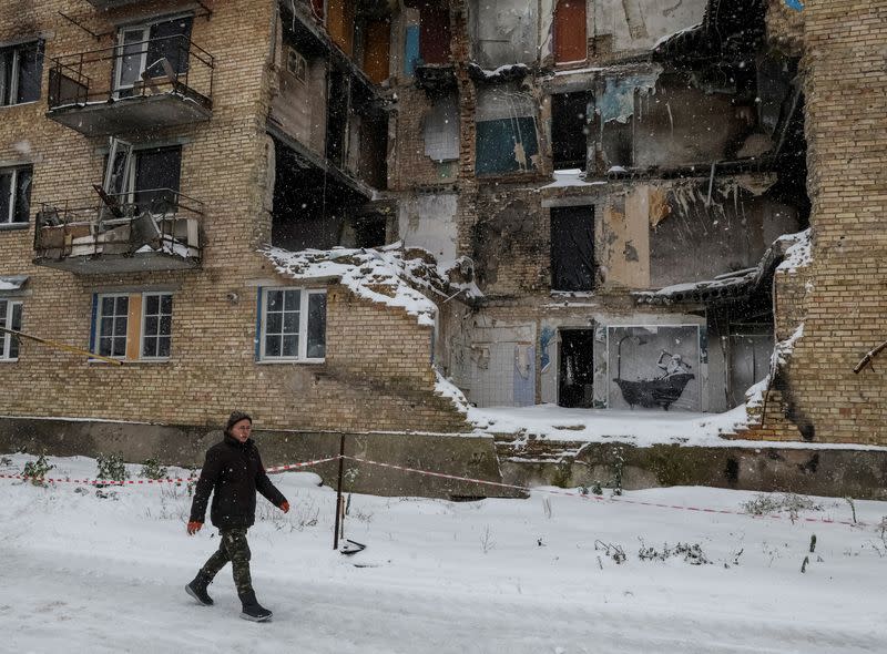 Local resident Reznychenko walks near a work of world-renowned graffiti artist Banksy at the wall of destroyed building in the Ukrainian village of Horenka