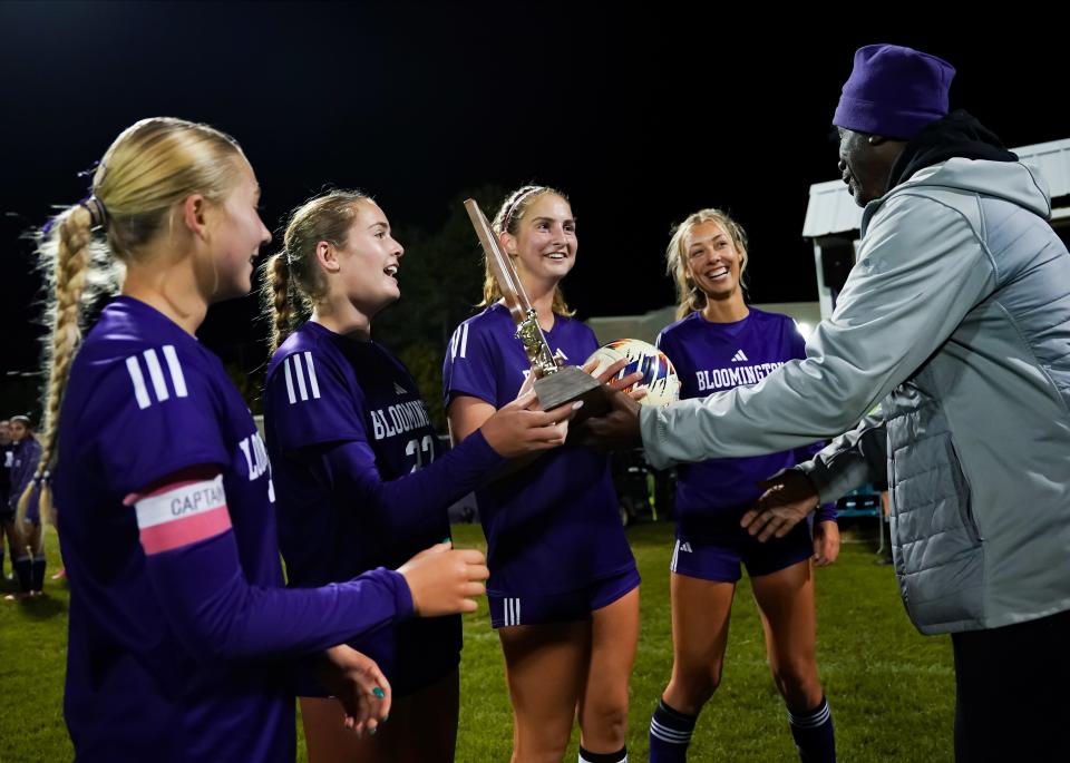 Bloomington South’s Zoe Kunzman (left), Katharine Lacy, Annalise Coyne and Keira Robinson receive the trophy from assistant Athletic Director Larry Winters after the IHSAA Girls’ soccer sectional championship game at Bloomington South on Saturday, Oct. 7, 2023.