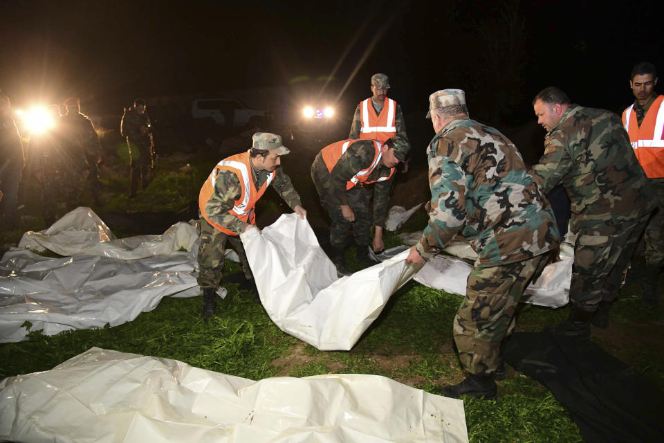 In this photo released Monday, Feb. 17, 2020 by the Syrian official news agency SANA, Syrian security forces check human remains at the site of a mass grave believed to contain the bodies of civilians and troops, in Douma, near the Syrian capital Damascus. Syrian state media reported that authorities have exhumed nearly 70 bodies of civilians and soldiers including a woman, most of them shot at close range. (SANA via AP)