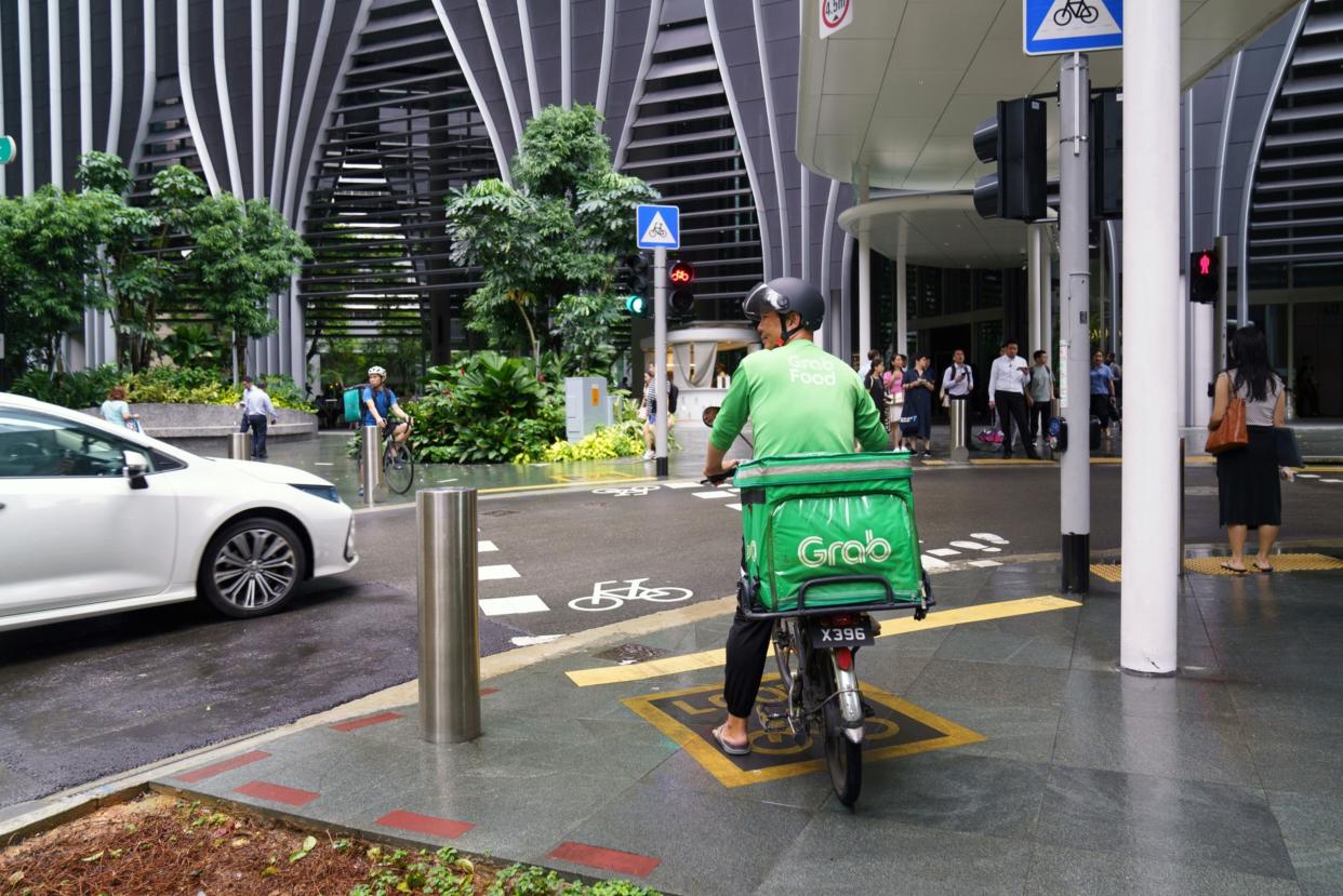 A Grab food delivery cyclist makes a delivery in Singapore. Photographer: Ore Huiying/Bloomberg