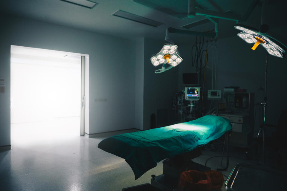 A vacant, well-lit hospital operating room with surgical lights illuminated over an empty operating table