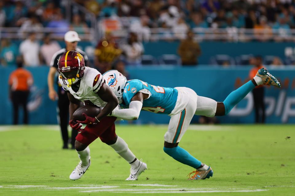 Aug 17, 2024; Miami Gardens, Florida, USA; Washington Commanders wide receiver Olamide Zaccheaus (14) runs with the football against Miami Dolphins cornerback Cam Smith (24) during the second quarter of a preseason game at Hard Rock Stadium. Mandatory Credit: Sam Navarro-USA TODAY Sports