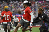 AFC wide receiver Davante Adams of the Las Vegas Raiders, center, pitches the ball back to AFC wide receiver Tyreek Hill (10) of the Miami Dolphins as NFC cornerback Jalen Ramsey of the Los Angles Rams defends during the flag football event at the NFL Pro Bowl, Sunday, Feb. 5, 2023, in Las Vegas. (AP Photo/David Becker)
