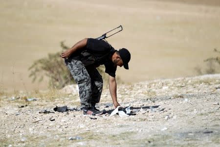 A rebel fighter from the Ahrar al-Sham Movement gathers pieces of the wreckage of an unidentified and unmanned aircraft that had crashed at their base in Maarchmarein village in the southern part of Idlib province, Syria October 20, 2015. REUTERS/Khalil Ashawi