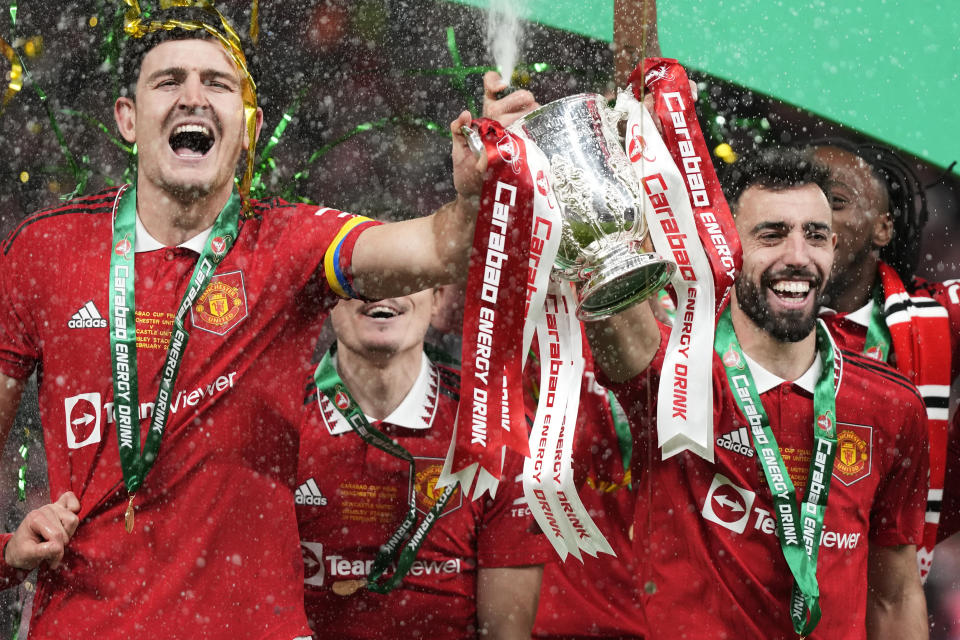 Manchester United's Harry Maguire, left, and Bruno Fernandes hold the trophy during celebration as they won the English League Cup final soccer match between Manchester United and Newcastle United at Wembley Stadium in London, Sunday, Feb. 26, 2023. (AP Photo/Alastair Grant)