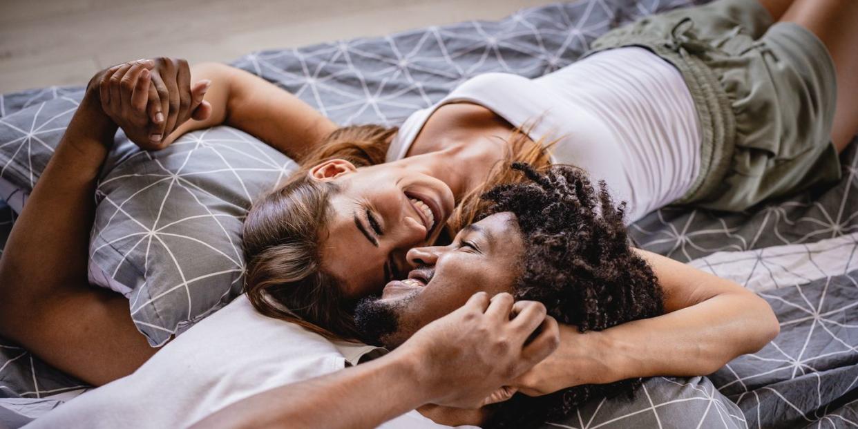 young couple lying bed in bedroom and smiling