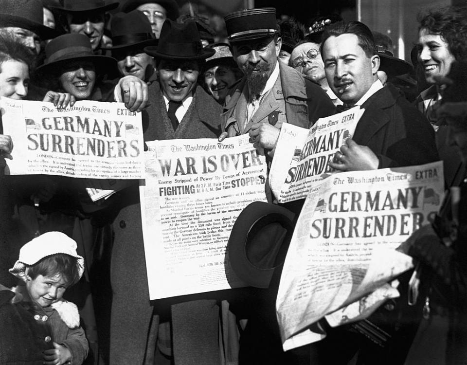 Crowd of people celebrating with newspapers declaring the end of a war