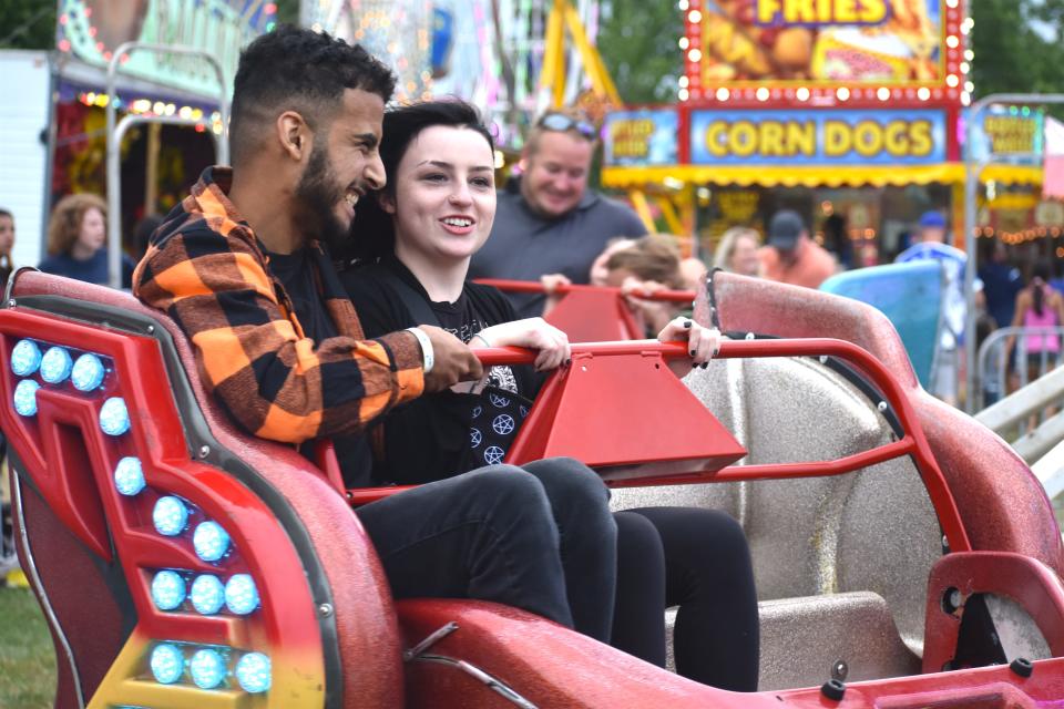 Mustafa Alkhafahjai, left, of Ann Arbor and Phoebe Brown of Blissfield smile July 10, 2021, as they ride on the Sizzler in Blissfield's Ellis Park during the River Raisin Festival. Midway rides and carnival games are once again being supplied this year by Maple Leaf Amusements.