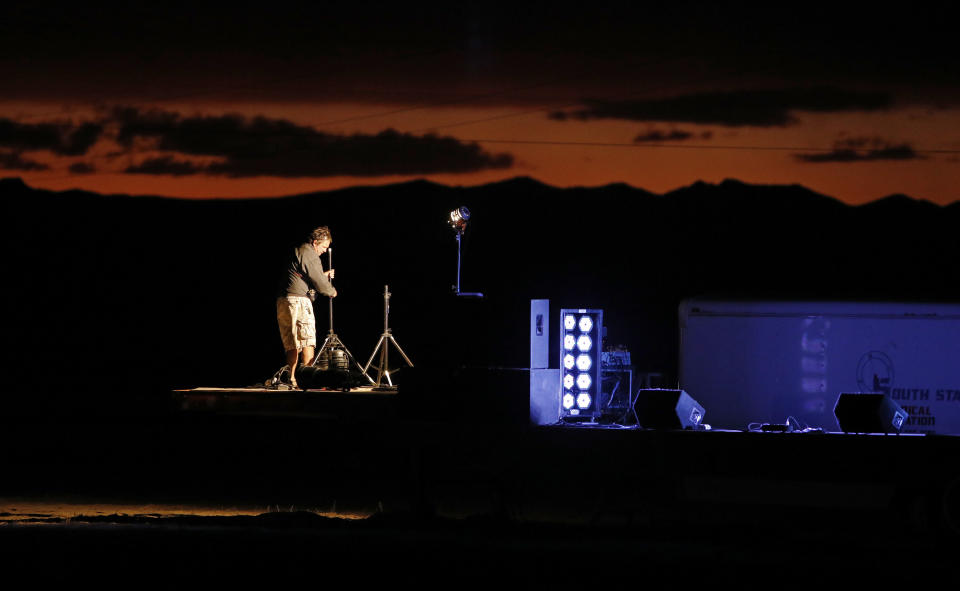 A man sets up a stage in preparation for an event inspired by the "Storm Area 51" internet hoax near the Little A'Le'Inn motel and cafe, Thursday, Sept. 19, 2019, in Rachel, Nev. Hundreds have arrived in the desert after a Facebook post inviting people to "see them aliens" got widespread attention and gave rise to festivals this week. (AP Photo/John Locher)