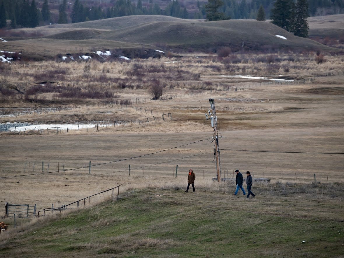 People walk on the former grounds of St. Joseph's Mission Residential School, on March 30, 2022. In January, the Williams Lake First Nation announced it had identified 93 'reflections' that could indicate the number of bodies buried around the site of the former residential school.  (Darryl Dyck/The Canadian Press - image credit)