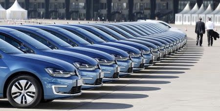 People walk past a row of Volkswagen e-Golf cars during the company's annual news conference in Berlin in this March 13, 2014 file picture. In recent weeks, the economy that proud German politicians have taken to describing as a "growth locomotive" and "stability anchor" for Europe, has been hit by a barrage of bad news that has surprised even the most ardent Germany sceptics. The big shocker came on August 14, 2014, when the Federal Statistics Office revealed that gross domestic product (GDP) had contracted by 0.2 percent in the second quarter. Picture taken March 13, 2014. TO MATCH STORY GERMANY-ECONOMY/ REUTERS/Tobias Schwarz/Files (GERMANY - Tags: BUSINESS TRANSPORT)