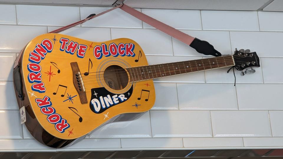 A guitar hangs on the wall inside the Round The Clock Diner.