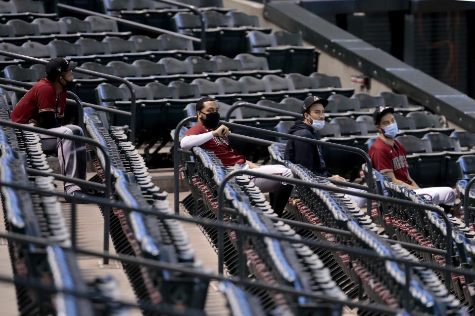 FILE - In this July 16, 2020, file photo, Arizona Diamondbacks players watch from the stadium seats during an intrasquad game at Chase Field, in Phoenix. MLB has provided teams with a 113-page operations manual detailing protocols for its pandemic-shortened 60-game regular season. Players will be tested every 48 hours. Masks and social distancing are a must at all times, except on the field. Backups will watch games from the stands instead of the dugout. No sunflower seeds. No spitting. No licking fingers. (AP Photo/Matt York, File)