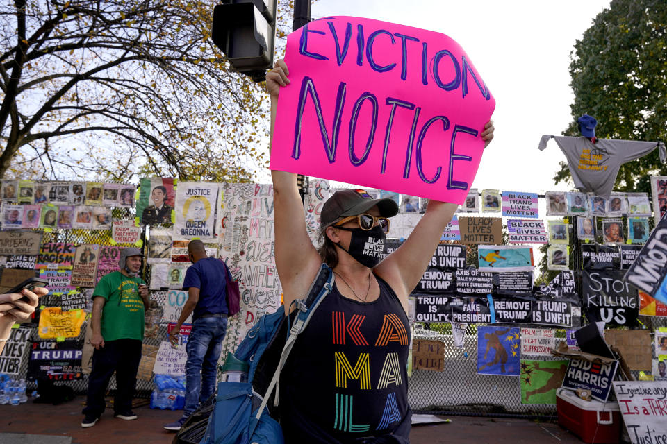 Jenn Katchmark, of Washington, holds up an eviction sign intended for Pres. Donald Trump while walking through Black Lives Matter Plaza, Thursday, Nov. 5, 2020, in Washington. (AP Photo/Jacquelyn Martin)