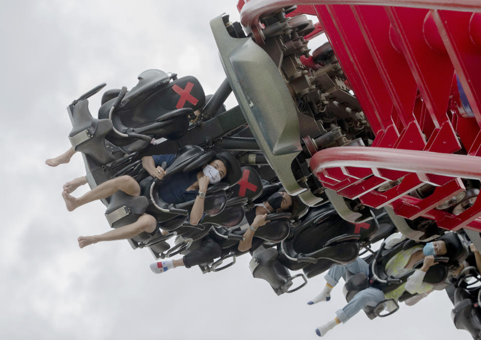 Visitors wear their face masks to help curb the spread of the coronavirus, as they ride the "Vortex" rollercoaster at the recently reopened Siam Amazing Park in in Bangkok, Thailand, Wednesday, June 17, 2020. Daily life in the capital resumes to normal as the government continues to ease restrictions related to running business and activities that were imposed weeks ago to combat the spread of COVID-19. Thailand reported no local transmissions of the coronavirus in the past 3 weeks. (AP Photo/Sakchai Lalit)