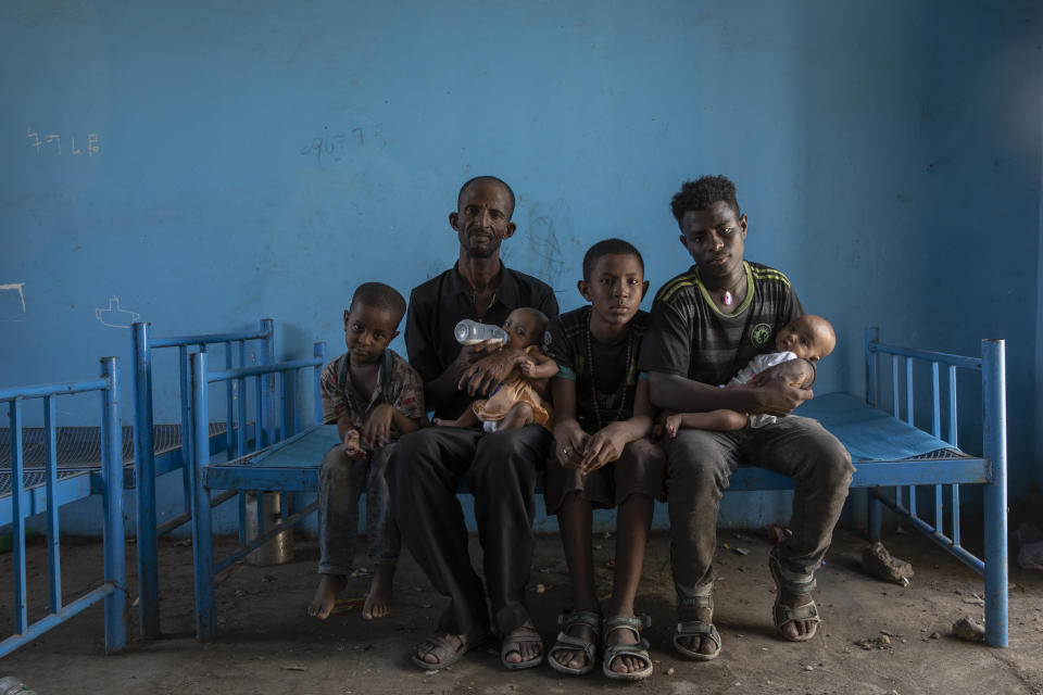 Abraha Kinfe Gebremariam (segundo por la izquierda), un refugiado de Tigray de 40 años, posa para una fotografía con sus hijos Micheale (izquierda), de 5 años, y Daniel (centro), de 11; su cuñado Goytom Tsegay (segundo por la derecha), de 19 años, y sus gemelas de 4 meses, Aden (derecha) y Turfu Gebremariam (en sus brazos), dentro del albergue donde vive la familia en Hamdayet, en el este de Sudán, cerca de la frontera con Etiopía, el 23 de marzo de 2021. Otra refugiada, Mulu Gebrencheal, madre de cinco hijos, se ha convertido en su asesora, ofreciéndole consejos para el cuidado de los bebés. Abraha y sus hijos aprenden rápido, añadió lamentando la muerte de la madre. (AP Foto/Nariman El-Mofty)