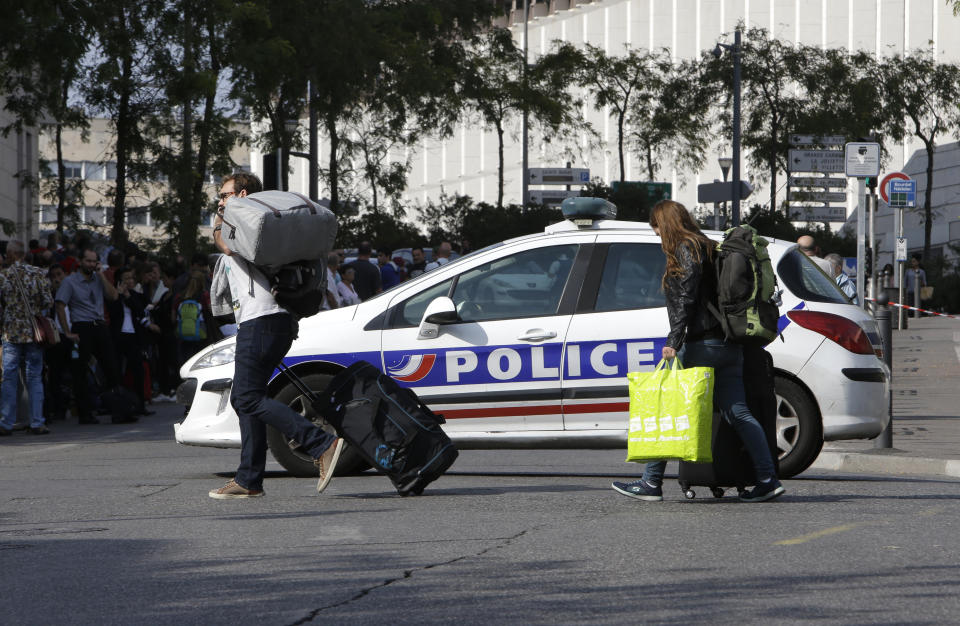 <p>Passengers cross the street by a police car blocking the access to Marseille ‘s main train station, Oct. 1, 2017 in Marseille, southern France. French police have warned people to avoid Marseille’s main train station following a knife attack that made at least one dead. (AP Photo/Claude Paris) </p>