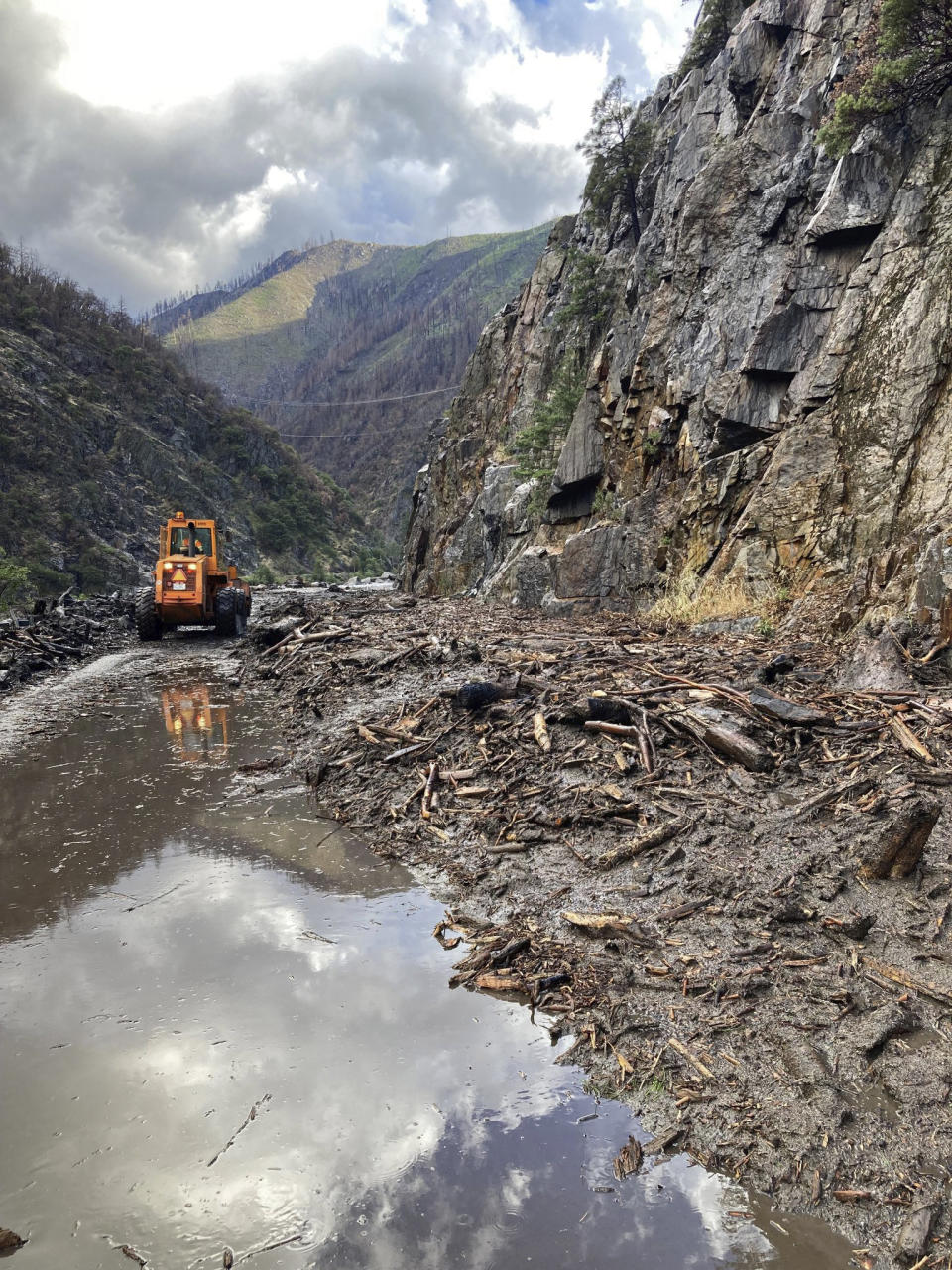 In this photo provided Caltrans, crews work to clear a multiple slides along Highway 70 in the Feather River Canyon near Belden, Calif., Sunday, June 12, 2022. A 50-mile (80-km) stretch of the highway was closed indefinitely on Monday after mud, boulders and dead trees inundated lanes during flash floods along a wildfire burn scar. There was no estimate for when the mountain route might reopen. (Caltrans via AP)