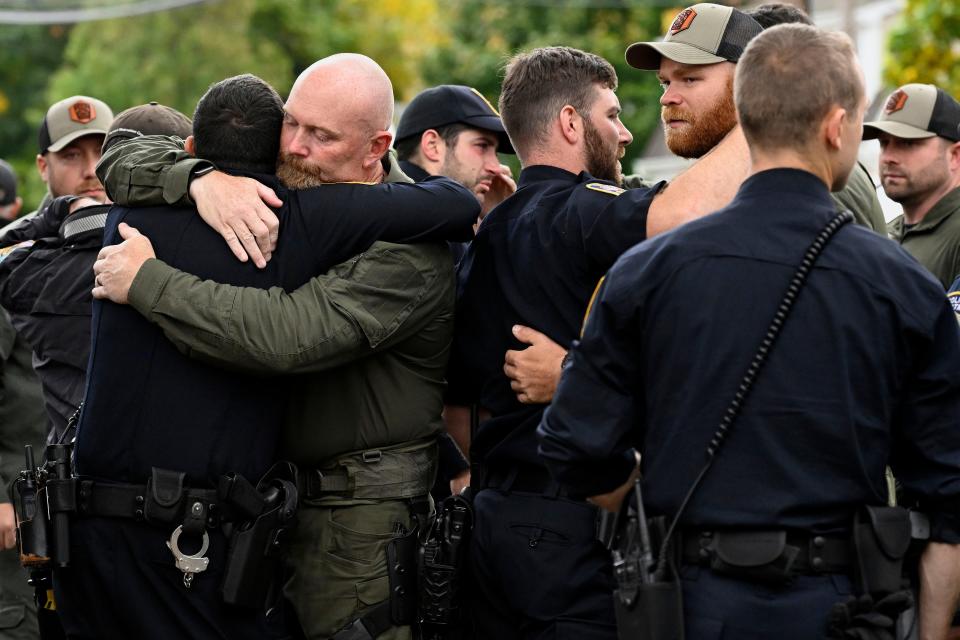 Bristol Police officers console one another at the scene where two police officers killed, Thursday, Oct. 13, 2022, in Bristol, Conn. The officers were fatally shot and a third wounded while responding to a domestic violence call in Connecticut, authorities said Thursday, amid an exceptionally violent week for officers across the country.