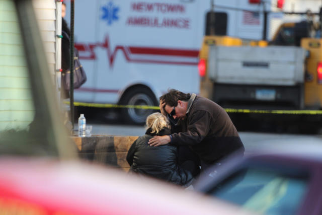 A man, burying his head in his hands, comforts a woman outside a fire station near Sandy Hook Elementary School.