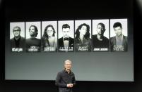 Apple Inc CEO Tim Cook talks about the iTunes Festival with some of the artists expected in the background during Apple Inc's media event in Cupertino, California September 10, 2013. (REUTERS/Stephen Lam)