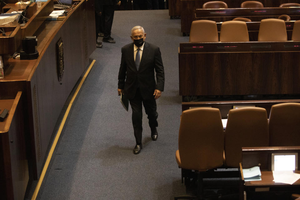 FILE - Former Israeli Prime Minister Benjamin Netanyahu walks during a session of the Knesset, Israel's parliament, in Jerusalem, Monday, Oct. 4, 2021. Netanyahu watched from the sidelines Thursday, as the government that toppled him after 12 years in power passed a national budget, dealing a major blow to his hopes of a swift return to the country's top office.(AP Photo/Ariel Schalit, File)