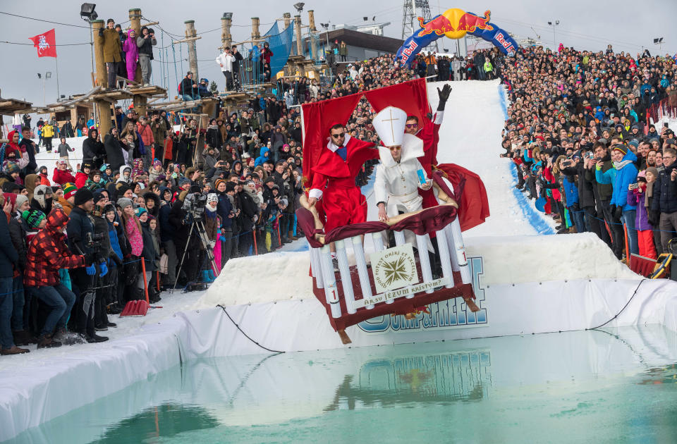 <p>Teilnehmer des „Red Bull Jump & Freeze Festivals“ in Litauens Hauptstadt Vilnius rutschen als Papst und Kardinäle verkleidet von einem Hang in den eisigen Pool. (Bild: Xinhua/ddp Images) </p>