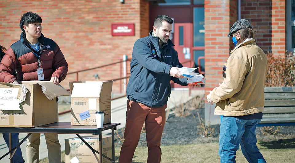 Quincy Public Health Commissioner Marli Caslli, center, hands out COVID test kits and KN95 masks to a city resident on Tuesday, March 8, 2022.