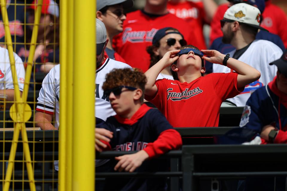 A Cleveland Guardians fan looks up at the solar eclipse before the home opener against the Chicago White Sox at Progressive Field on April 8, 2024 in Cleveland, Ohio.