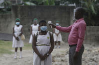 FILE - In this Aug. 4, 2020, file photo, a teacher checks students for fever at Lagos State Model School in Lagos, Nigeria. The coronavirus pandemic has fractured global relationships as governments act in the interest of their citizens first, but John Nkengasong, Africa's top public health official, has helped to steer the continent's 54 countries into an alliance praised as responding better than some richer nations. (AP Photo/Sunday Alamba, File)