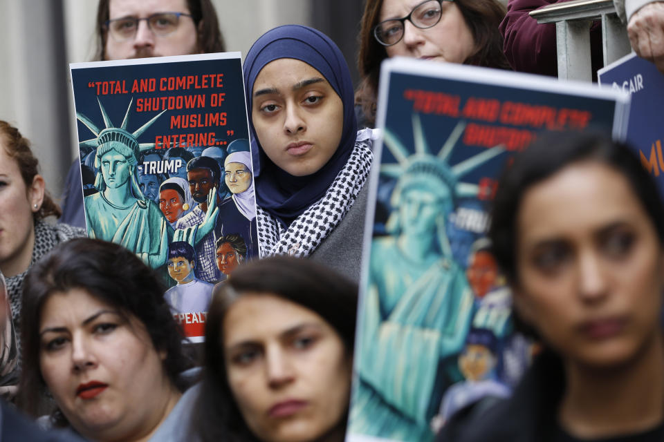 Demonstrators listen to speakers during a rally outside the U.S. 4th Circuit Court of Appeals Tuesday Jan 28, 2020, in Richmond, Va. President Donald Trump's travel ban on travelers from predominantly Muslim countries is going back before a federal appeals court. On Tuesday, the 4th U.S. Circuit Court of Appeals in Richmond will hear arguments in three lawsuits filed by U.S. citizens and permanent residents whose relatives have been unable to enter the U.S. because of the ban. (AP Photo/Steve Helber)