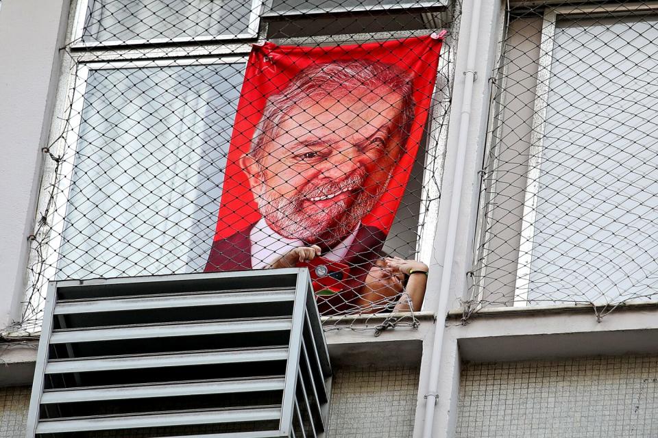 A woman blows kisses while poster hangs on window.