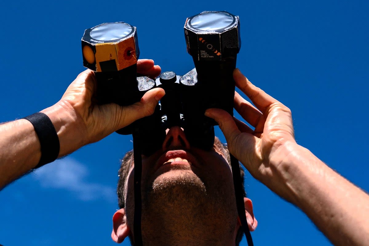 Frederik De Vries looks up at the sun during the solar eclipse using binoculars outfitted with special film in Washington, DC, on 8 April, 2024 (Getty Images)