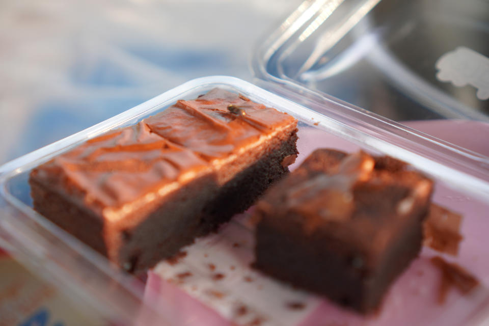 Two pieces of chocolate brownie in a clear plastic container, with a shiny chocolate glaze on top