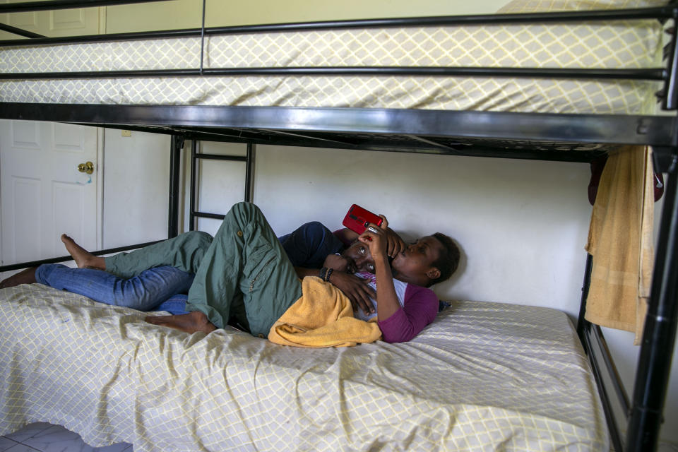 Transgenders Johnson Losier and her partner Volcy Kluvens, watch a movie as they lie on a bed at the Kay Trans Haiti center in Port-au-Prince, Haiti, Tuesday, Aug. 4, 2020. Funded by a Spanish healthcare company and the United Nations Development Program, the center is open to transgender people who have been victims of verbal or physical abuse. (AP Photo/Dieu Nalio Chery)