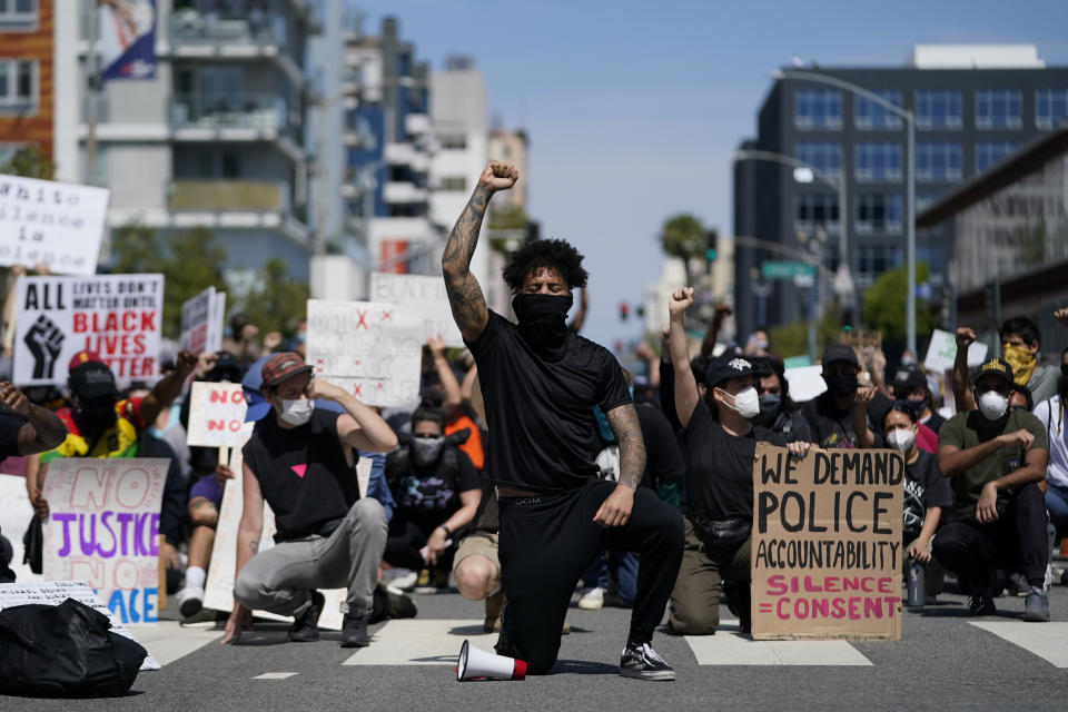 FILE - In this May 31, 2020, file photo, demonstrators kneel in a moment of silence outside the Long Beach Police Department in Long Beach during a protest over the death of George Floyd. Proposed federal legislation that would radically transform the nation's criminal justice system through such changes as eliminating agencies like the Drug Enforcement Administration and the use of federal surveillance technology is set to be unveiled Tuesday, July 7, by the Movement for Black Lives. (AP Photo/Ashley Landis, File)