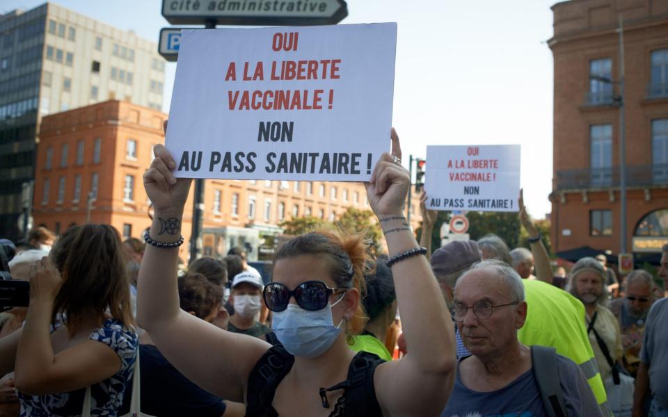 A woman holds a placard reading 'Yes to vaccination freedom, no to the health pass' - Getty