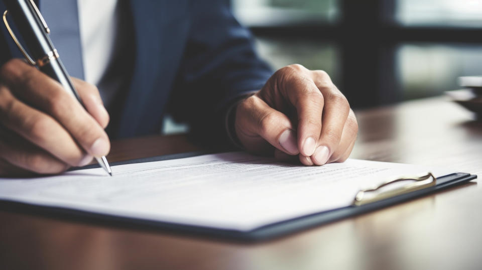 A close up of a worker signing a document, illustrating the company's commitment to credit protection products.