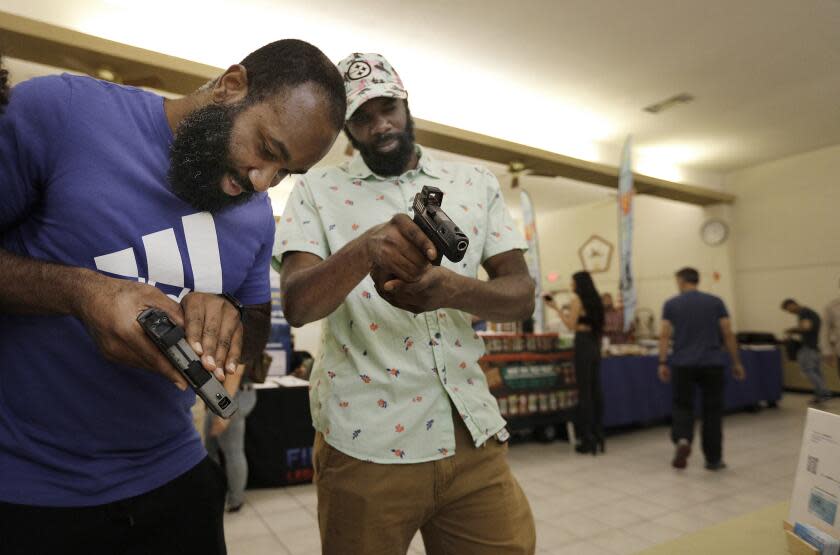 SAN DIEGO, CA OCTOBER 21, 2023 - The San Diego Gun Show held at the East San Diego Masonic Lodge drew crowds to the event hosted by the San Diego County Gun Owners Political Action Committee (PAC). At this event Halim Abdullah, left, and cousin Basil Henry, both of San Diego, look at a sight accessory created by San Diego's 2C Optic Cut service. (John Gastaldo / For The Times)