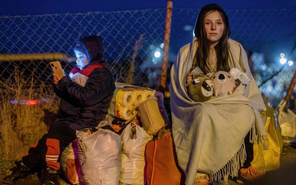 Helena (R) and her brother Bodia (L) from Lviv are seen at the Medyka pedestrian border crossing, in eastern Poland, after fleeing Ukraine - WOJTEK RADWANSKI/AFP