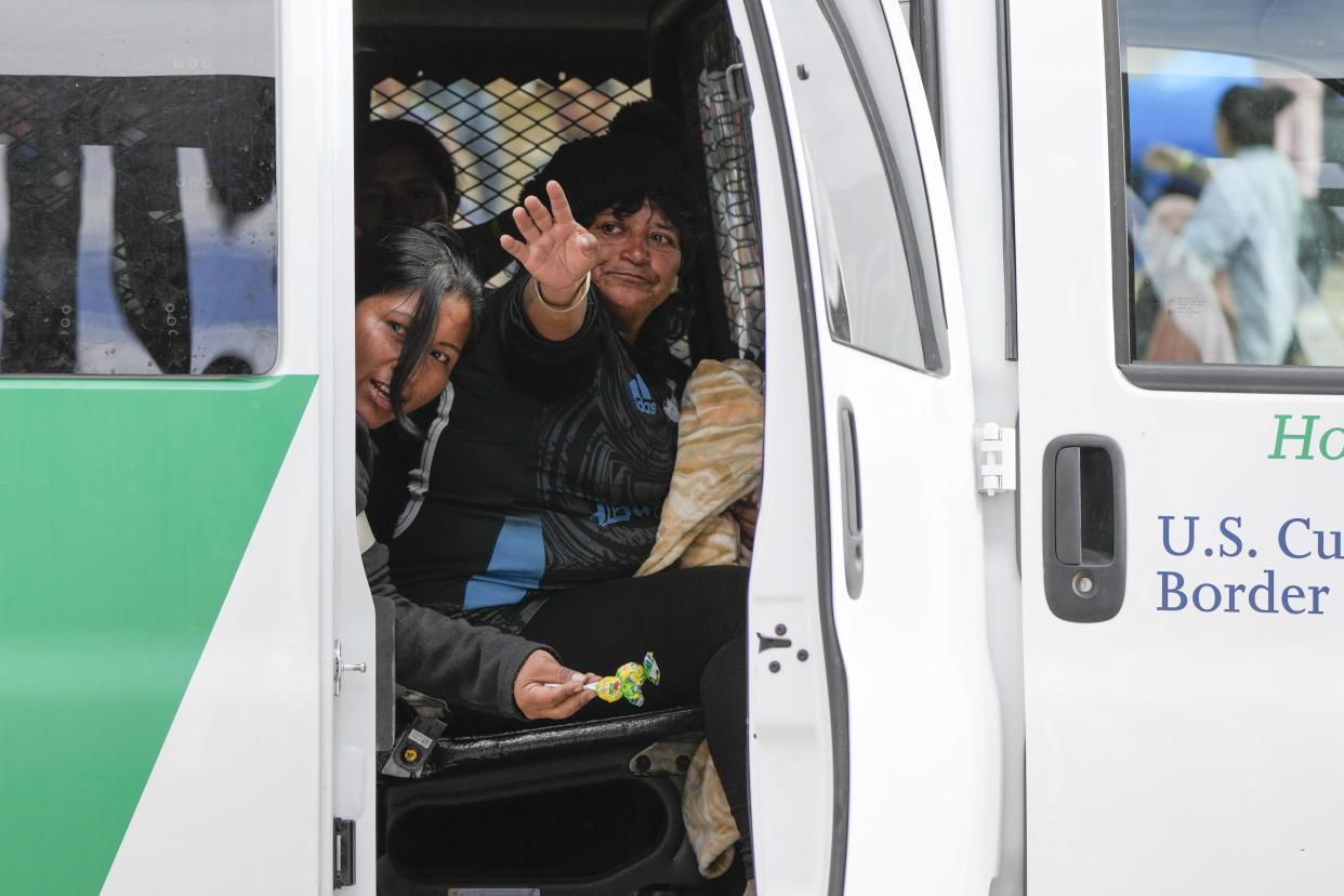 A woman waves to friends in a U.S. Border Patrol van after waiting to apply for asylum between two border walls Thursday, May 11, 2023, in San Diego. Many of the hundreds of migrants between the walls that separate Tijuana, Mexico, with San Diego have been waiting for days to apply for asylum. Pandemic-related U.S. asylum restrictions, known as Title 42, are to expire May 11. (AP Photo/Gregory Bull)