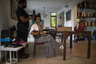 A hairdresser styles the hair of businesswoman Magalie Dresse before she begins a full workday of meetings, in Port-au-Prince, Haiti, Tuesday, Sept. 14, 2021. Since 2004, her car has been attacked; she has survived two kidnapping attempts; the government expropriated some of her properties; and her factory was damaged by arson in riots, costing her $400,000 in a single day. (AP Photo/Rodrigo Abd)