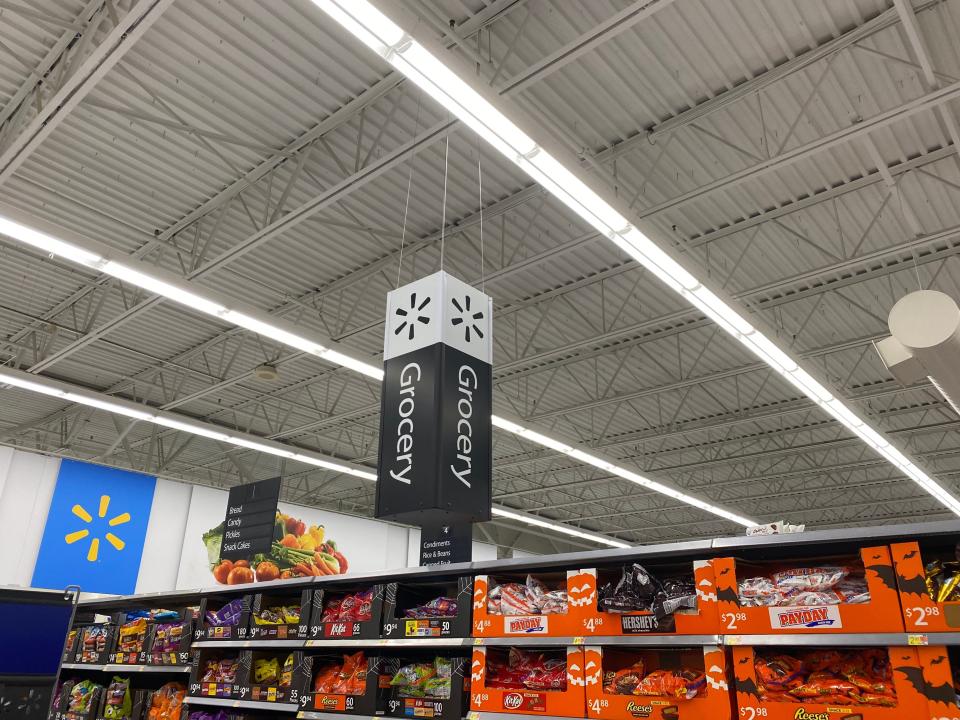A sign that reads "grocery" hanging above shelves of candy in a walmart
