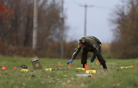 A Surete du Quebec (SQ) officer investigates the scene of a police shooting in Saint-Jean-sur-Richelieu, Quebec October 20, 2014. REUTERS/Christinne Muschi